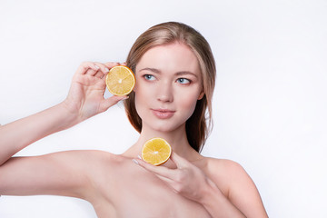 portrait of pretty young woman holding slices of orange, facial care