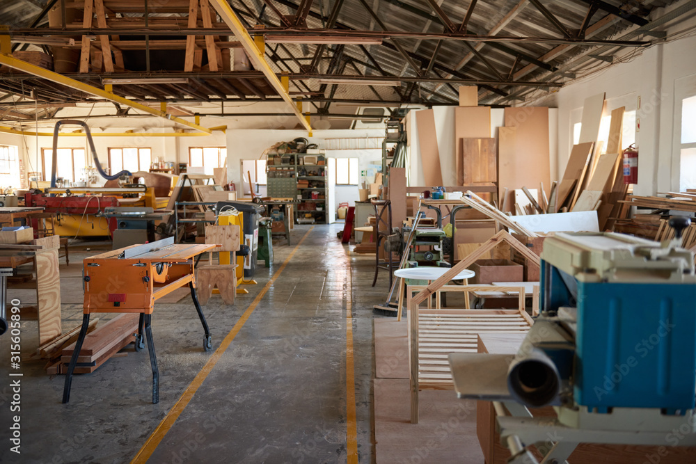 Wood and machinery in a large carpentry workshop - obrazy, fototapety, plakaty 