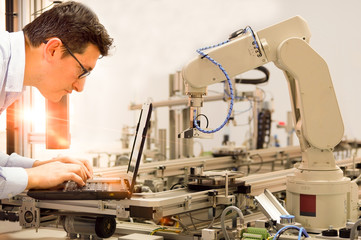close-up of an engineer who is working on laptop to program robot arm