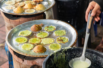 Wall Mural - Making fresh coconut pancakes, They are made from coconut cream, rice flour and sugar, Pouring cream in the pan on stove, Sweet street snacks, Luang prabang, Laos.