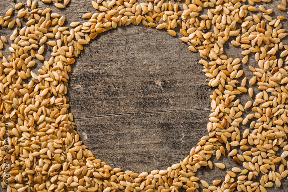 Golden flax seeds on wooden table. Copy space - obrazy, fototapety, plakaty 