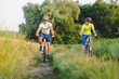 © sergo321 - young man and woman ride bicycles between fields in summer.