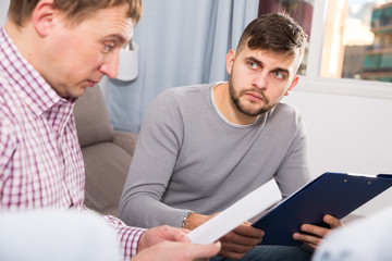 Wall Mural - Upset man with friend looking at papers on sofa