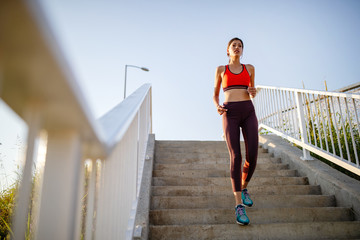 Wall Mural - Portrait of fit cheerful woman resting after a run in a city