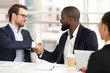 © fizkes - Diverse male partners handshake closing deal at meeting