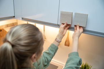 Wall Mural - woman choosing kitchen cabinet materials from laminate samples