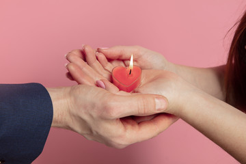 Wall Mural - valentine's day celebration, close up of caucasian couple's hands holding heart shaped candle on cor
