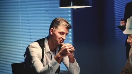 Wall Mural - Close-up of police detective is threatened with a weapon during interview. There is also his colleague in interrogation room with him.