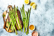 Bunch of fresh green asparagus on wooden board with olive oil, lemon and seasonings. Top view, copy space