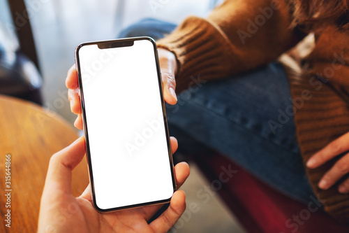 Fotografía Mockup image of a woman holding and showing white mobile phone with blank black