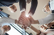 © AnnaStills - Low angle view of business team holding hands and cooperating with each other during team work at office