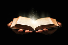 Man Holds Holy Bible Book On Black Background.