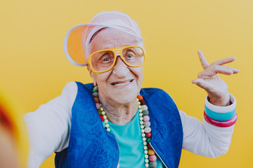 Funny grandmother portraits. 80s style outfit. trapstar taking a selfie on colored backgrounds. Concept about seniority and old people