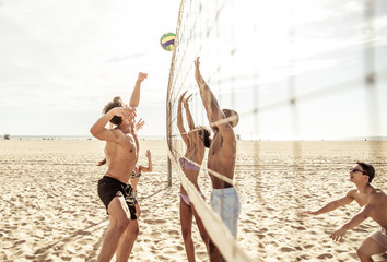 Group of friends playing beach volley on the beach.