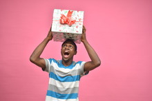 Excited Young Black Man Holding Large Gift Box On His Head Looking Surprised