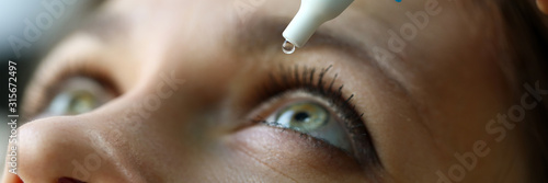 Fotomural Female putting liquid drops in her eye solving vision problem