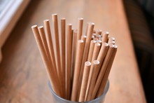 Eco Friendly Reusable Straws In The Cardboard Cup With Selective Focus And Blurred Ba. Paper Cocktail Tubes. Kraft Paper Straw For Drinking Coffee Or Tea. Disposable Cocktail Tube. 