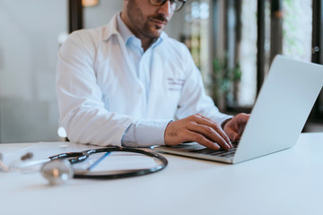 Close-up image of a doctor working on laptop.