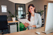 © bnenin - Portrait of a beautiful female entrepreneur, holding documents at work desk in the office.