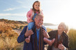 © Monkey Business - Grandfather Giving Granddaughter Ride On Shoulders As They Walk Through Sand Dunes With Grandmother