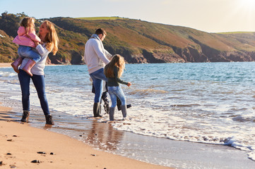 Wall Mural - Family Playing On Beach Jumping Over Waves Looking Out To Sea