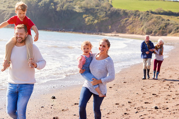 Wall Mural - Multi-Generation Family Walking Along Shoreline Of Beach By Waves Together