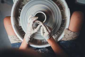 Wall Mural - Top view of female potter's hands working on pottery wheels with eco friendly clay makes mug, concept for workshop and master class, Handcraft Ceramic Art People 