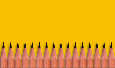 Brown pencils placed on yellow color paper background with copy space for your image or text.