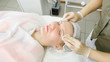 © lenblr - beauty salon therapist in white sterile gloves rinses patient face after laser hair removal close view