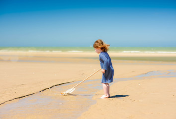 Wall Mural - cute little girl and her net for shrimp fishing on the beach