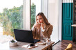 © Evgeniia - Beautiful business woman sitting in cafe and working. There are laptop, smartphone and cup of coffee. Woman enjoying her coffee while working.