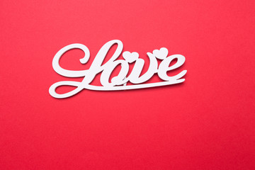 Lettering from wooden letters love on a red isolated background. Romantic postcard.