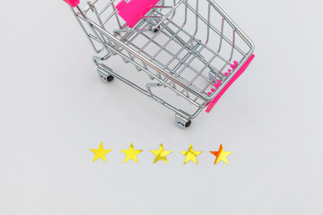 Small supermarket grocery push cart for shopping toy with wheels and 5 stars rating isolated on white background. Retail consumer buying online assessment and review concept.