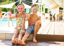 Portrait Of Happy Little Girl And Boy Wearing Mirrored Sunglasses Showing Their Popsicles