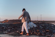 © Westend61 - Young man holding empty plastic bottles walking in barren land