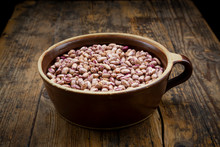 Bowl Of Dried Pinto Beans Lying On Wooden Table