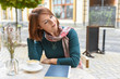 © Andrii - A young woman sits at a table in a summer cafe.