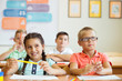 © spass - Cute schoolchildren study and answer questions in classroom during a lesson at primary school