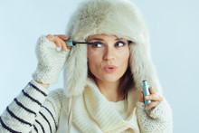 Woman Using Mascara Against Winter Light Blue Background