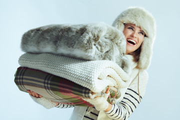 smiling young woman holding stack of warm blankets