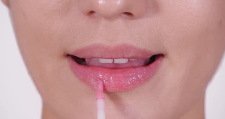 Poster - Beautiful young woman applying gloss on her perfect lips, closeup