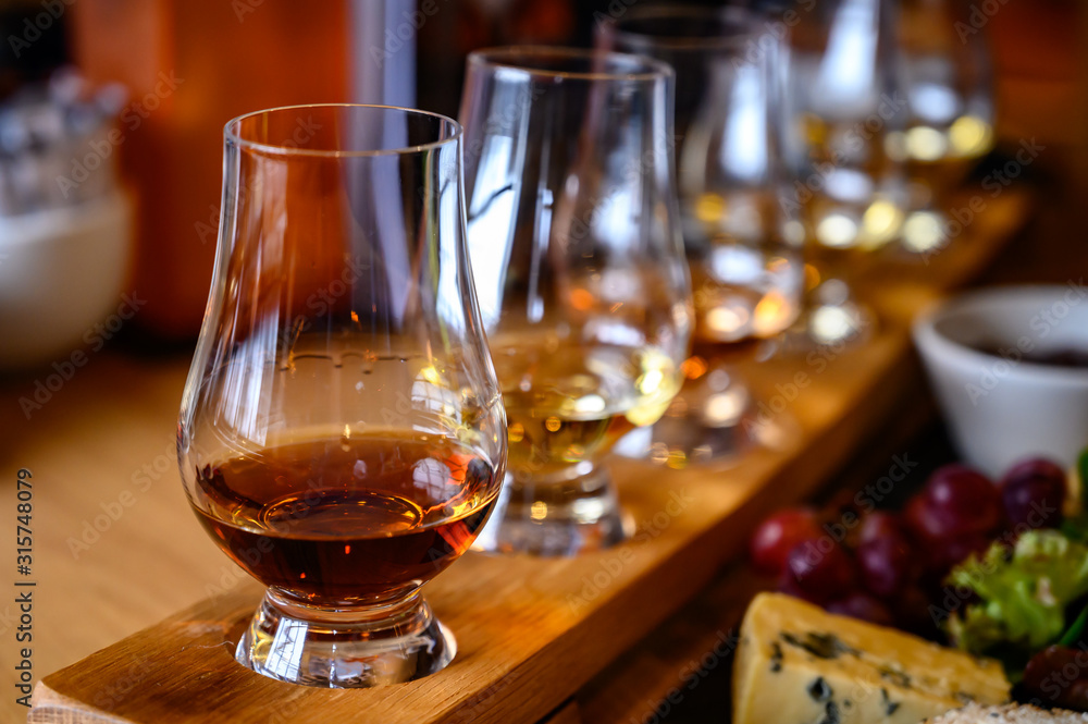 Scotch whisky, tasting glasses with variety of single malts or blended whiskey spirits on distillery tour in Scotland - obrazy, fototapety, plakaty 
