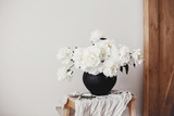 White peonies rural still life. Stylish peony bouquet in black clay vase on linen fabric with scissors on rustic background.Hello spring wallpaper. Happy Mothers day. Space text
