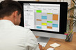 © New Africa - Man using calendar app on computer in office, closeup