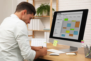 Canvas Print - Man using calendar app on computer in office