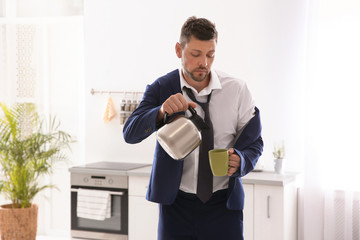 Canvas Print - Sleepy man pouring coffee into cup at home in morning