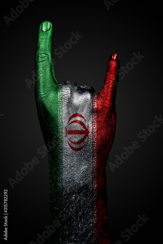 Fotomural A hand with a drawn Iran flag shows a goat sign, a symbol of mainstream, metal and rock music, on a dark background