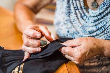 Wall Mural - older woman hand sewing clothing