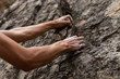 © Valmedia - Real life struggle concept as a man attempts to climb a steep rock face. Low angle view of arms struggling to find good grip positions. Copy space to right