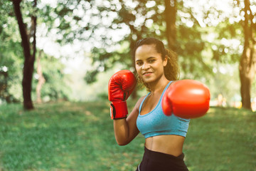 Sporty black woman boxer punching to you at park,Female boxer eye looking training to camera,Happy and smiling,Healthy and lifestyle concept